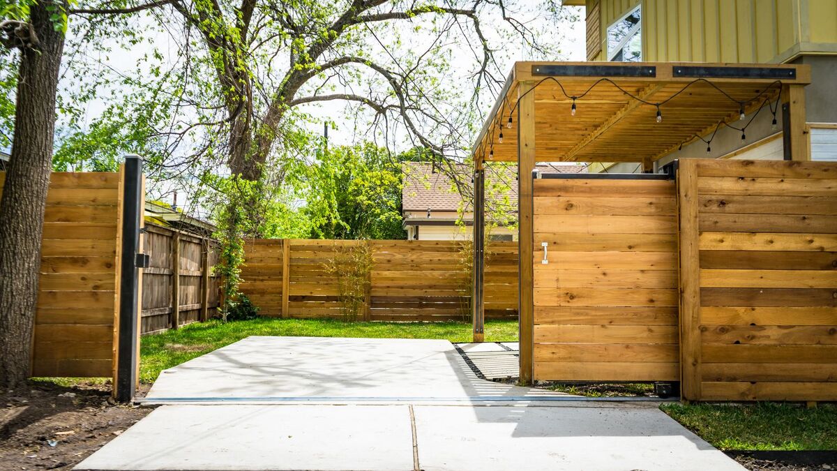 A new cedar-toned wood privacy fence with a matching gate beside a concrete patio